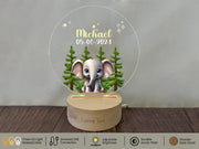 a personalized glass ornament with an elephant in a forest