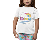 a little girl wearing a white shirt with a rainbow on it