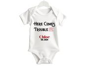 a white bodysuit with the words here comes trouble on it