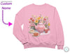 a pink sweater with a picture of a teapot and flowers on it